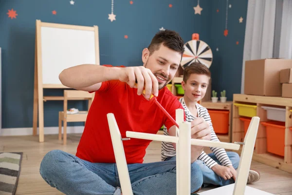 Father and his little son assembling furniture at home — Stock Photo, Image