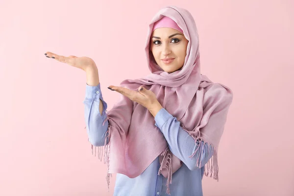 Mooie Arabische vrouw tonen iets op kleur achtergrond — Stockfoto
