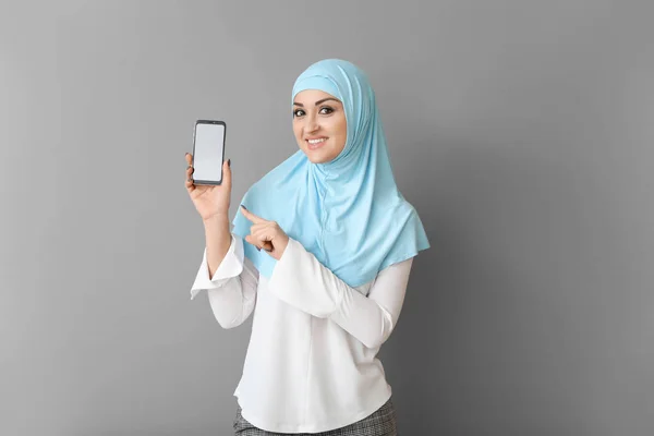 Mooie Arabische vrouw met mobiele telefoon op grijze achtergrond — Stockfoto