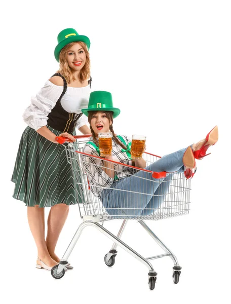 Divertidas mujeres jóvenes con cerveza y carrito de la compra sobre fondo blanco. Celebración del Día de San Patricio —  Fotos de Stock