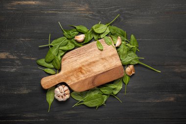 Üzerinde taze ıspanak ve sarımsak olan bir tahta.