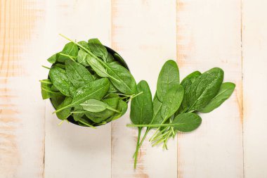 Beyaz ahşap arka planda taze ıspanaklı kase.