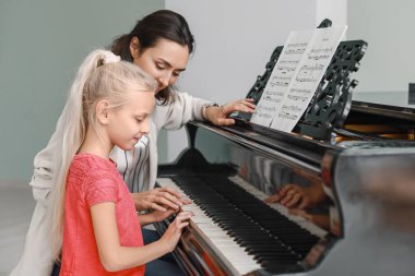 Özel müzik öğretmeni küçük kıza piyano dersleri veriyor.