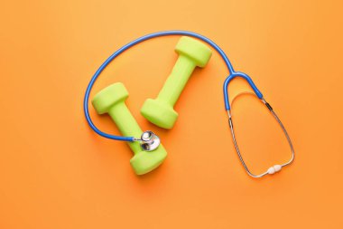 Renkli arkaplanda steteskop ve dambıllar