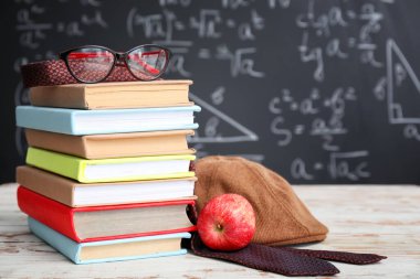 Sınıftaki masada okul kırtasiyesi ve elma seti.