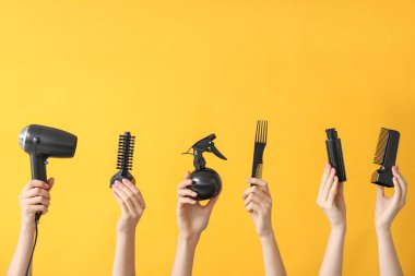 Renkli arka planda kuaför malzemeleri olan bir sürü el.