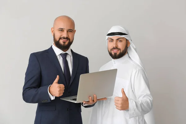 グレーの背景にノートパソコンを持つアラブ人男性と彼のビジネスパートナー — ストック写真