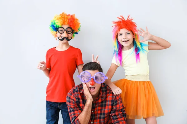 Family in funny disguise on light background. April fools' day celebration — Stock Photo, Image