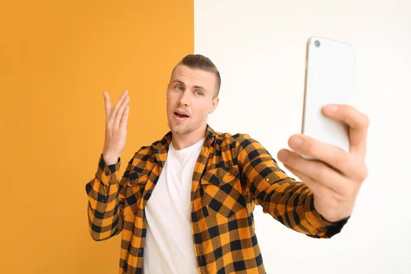 Handsome young man taking selfie on color background — Stock Photo, Image