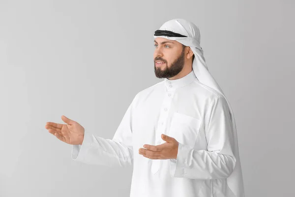 Handsome Arab man showing something on grey background