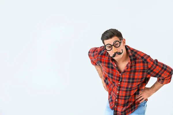 Man in funny disguise on light background. April fools' day celebration — Stock Photo, Image