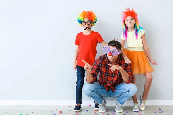 Family in funny disguise near light wall. April fools' day celebration — Stock Photo, Image