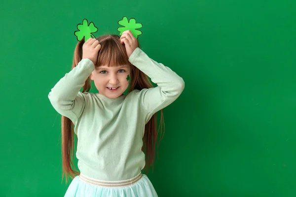 Funny little girl with clover on color background. St. Patrick's Day celebration — Stock Photo, Image