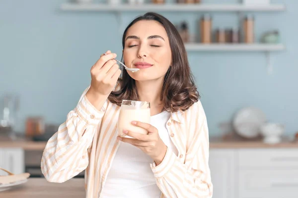 Jovem mulher comendo iogurte saboroso em casa — Fotografia de Stock