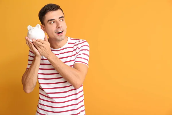 Happy man with piggy bank on color background — Stock Photo, Image