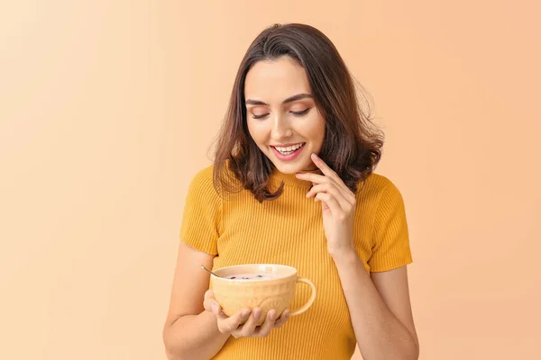 Junge Frau mit leckerem Joghurt auf farbigem Hintergrund — Stockfoto
