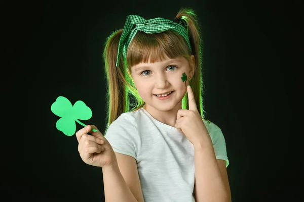 Funny little girl with clover on dark background. St. Patrick's Day celebration — Stock Photo, Image