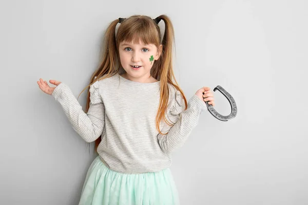 Funny little girl with horseshoe on white background. St. Patrick's Day celebration — Stock Photo, Image