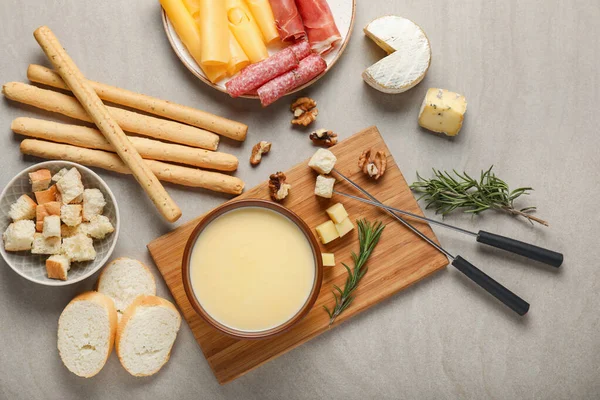 Cheese fondue with snacks on grey background — Stock Photo, Image
