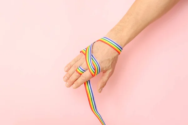 Чоловіча рука зі стрічкою веселки на кольоровому фоні. концепція ЛГБТ — стокове фото