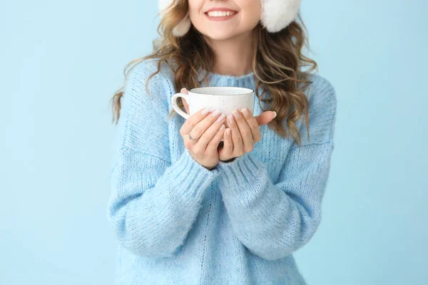 Vacker ung kvinna i varm tröja och med varmt te på färg bakgrund — Stockfoto