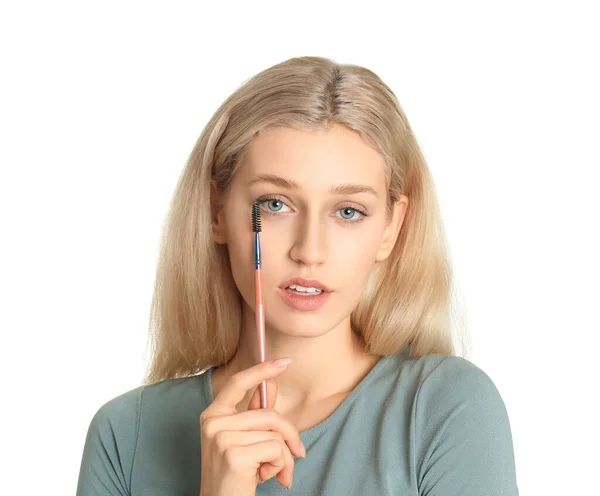 Beautiful young woman applying makeup on white background — Stock Photo, Image