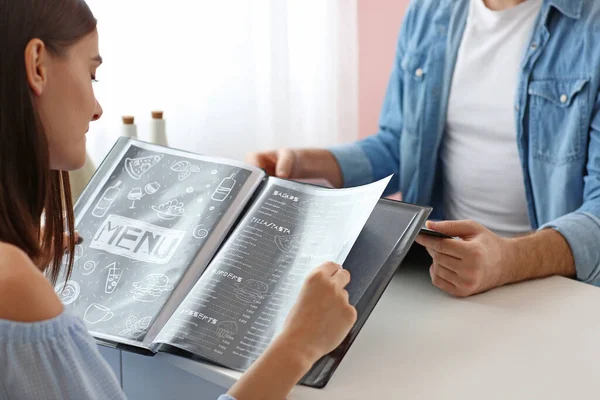 Young couple with menu sitting in restaurant — Stock Photo, Image