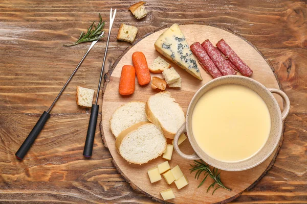 Fondue de queso con bocadillos sobre fondo de madera —  Fotos de Stock