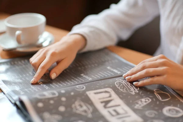 Молодая женщина с меню сидит в ресторане, крупным планом — стоковое фото
