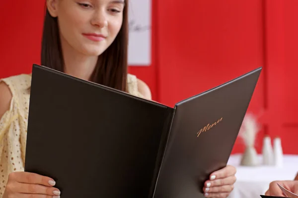 Young woman with menu sitting in restaurant — Stock Photo, Image