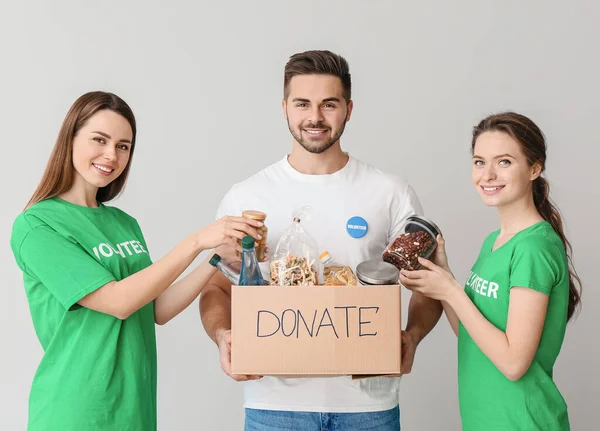 Voluntarios con donaciones para pobres sobre fondo claro — Foto de Stock