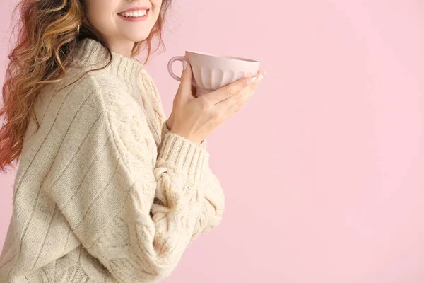 Bella giovane donna in maglione caldo e con tè caldo su sfondo di colore — Foto Stock