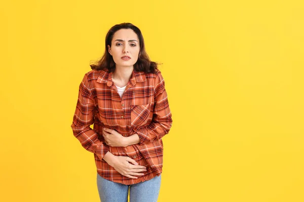 Young woman suffering from menstrual cramps on color background — ストック写真