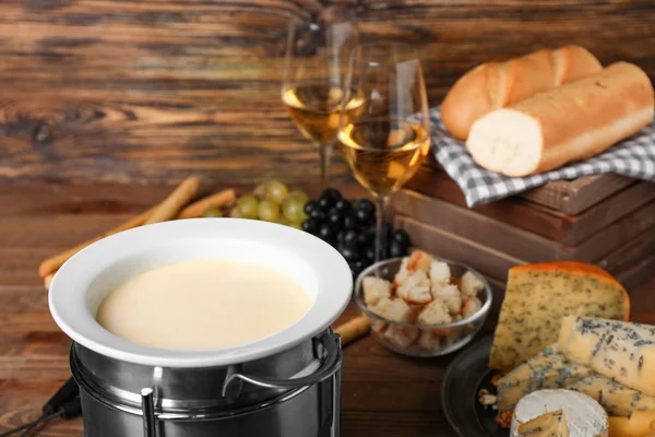 Fondue de queso con bocadillos sobre fondo de madera —  Fotos de Stock