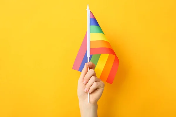 Mão feminina com bandeira do arco-íris no fundo de cor. Conceito LGBT — Fotografia de Stock