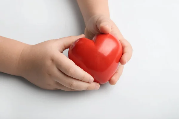 Дитячі руки з червоним серцем на білому тлі. Концепція кардіології — стокове фото