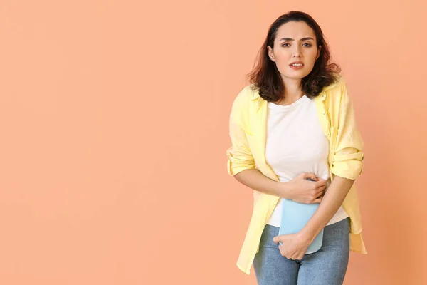 Mladá žena trpí menstruačními křečemi na barevném pozadí — Stock fotografie