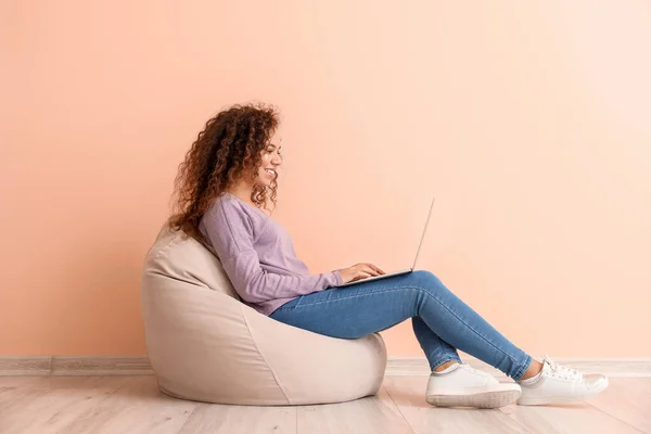 컬러 벽 근처에 노트북을 놓고 앉아 있는 젊은 흑인 여성 — 스톡 사진