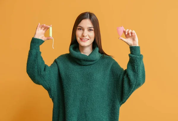 Mladá žena s menstruační pohár a tampón na barevném pozadí — Stock fotografie