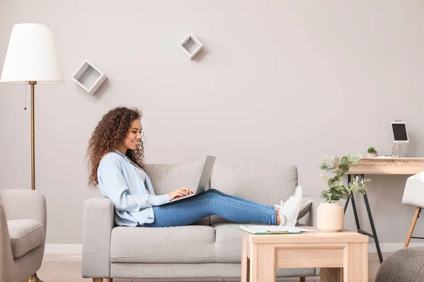 Young African-American woman with laptop working at home — Stock Photo, Image