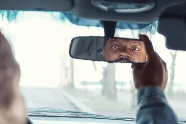 Bestuurder past achteruitkijkspiegel in auto aan — Stockfoto