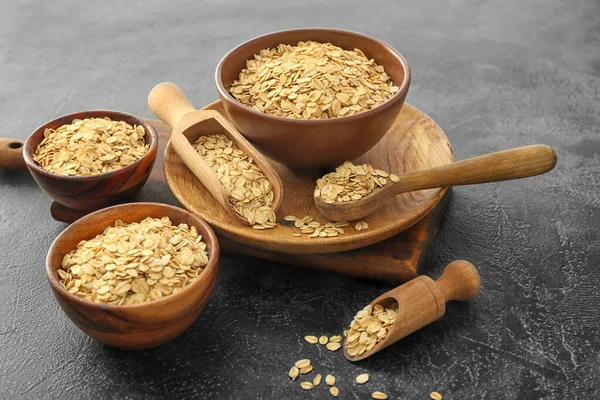 Bowls, scoops and spoon with raw oatmeal on table — Stock Photo, Image