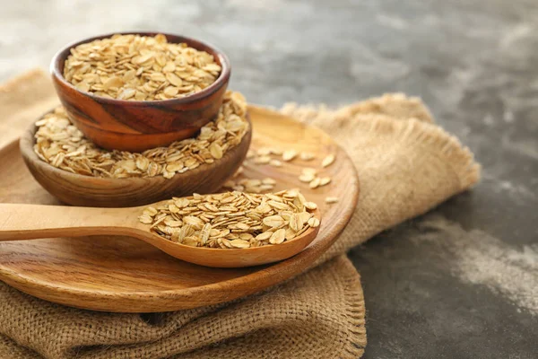 Bowls and spoon with raw oatmeal on table — Stock Photo, Image