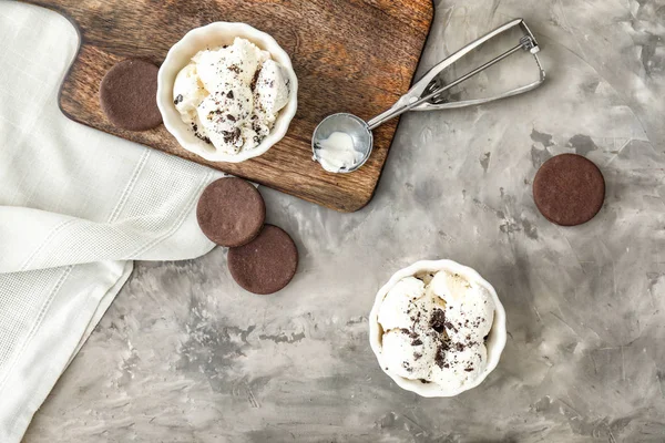 Tigelas com saboroso sorvete e biscoitos em fundo cinza — Fotografia de Stock