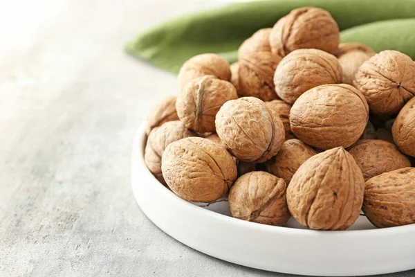 Plate with tasty walnuts on table — Stock Photo, Image