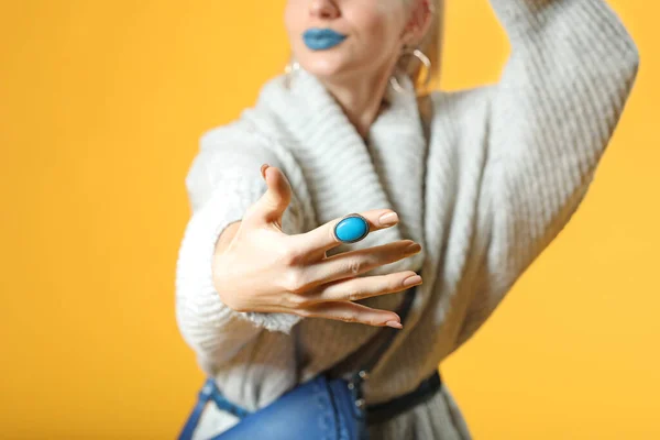 Jonge vrouw in warme trui en met stijlvolle ring op kleur achtergrond, closeup — Stockfoto