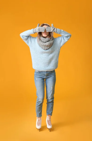 Beautiful young woman on ice skates against color background — Stock Photo, Image