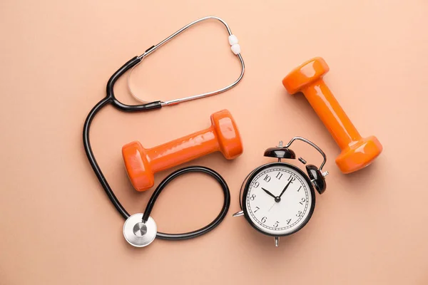 Stethoscope, clock and dumbbells on color background — Stock Photo, Image