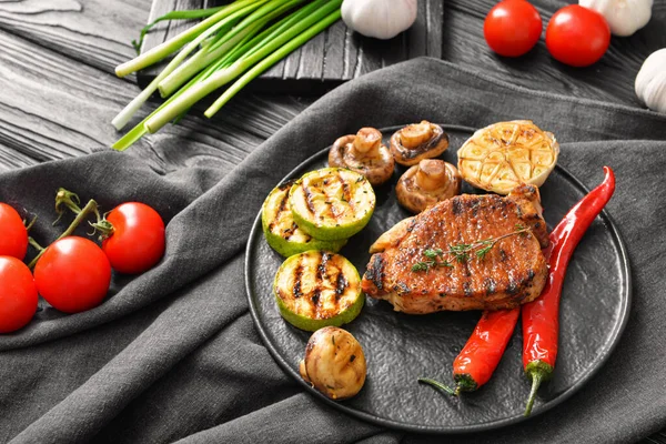 Assiette avec steak de porc cuit et légumes sur la table — Photo