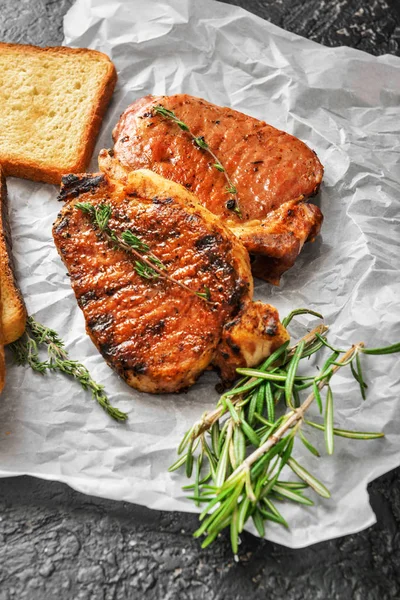 Gustose bistecche di maiale cotte con pane su sfondo scuro — Foto Stock